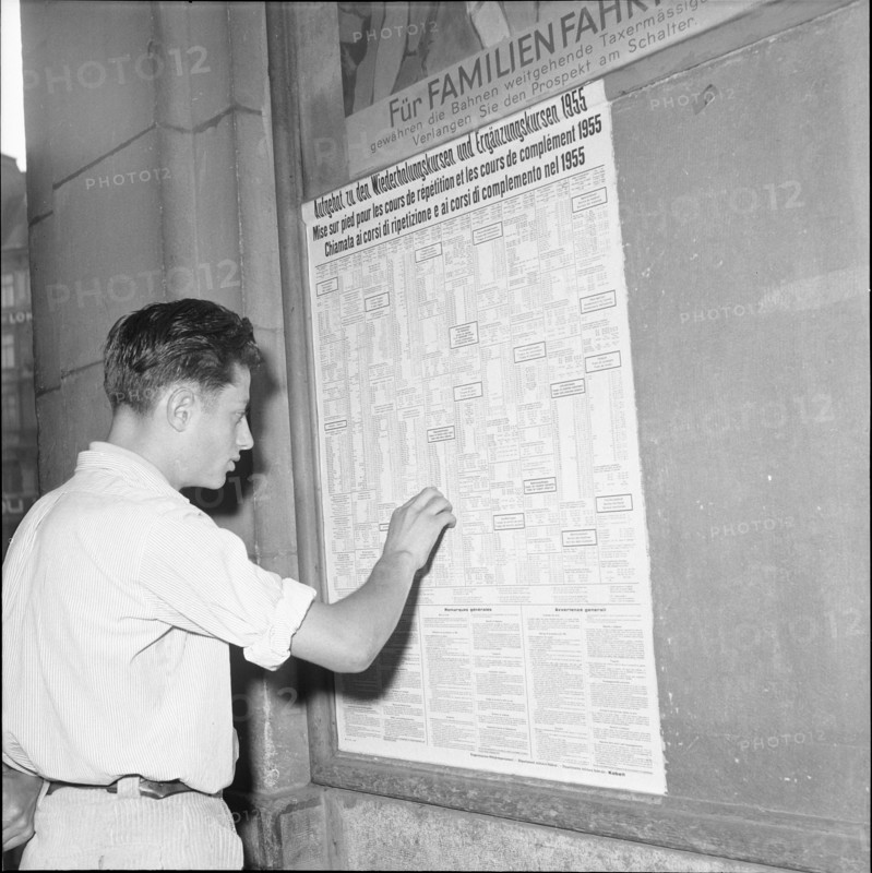 Man studies a levy poster for the World War, 1955