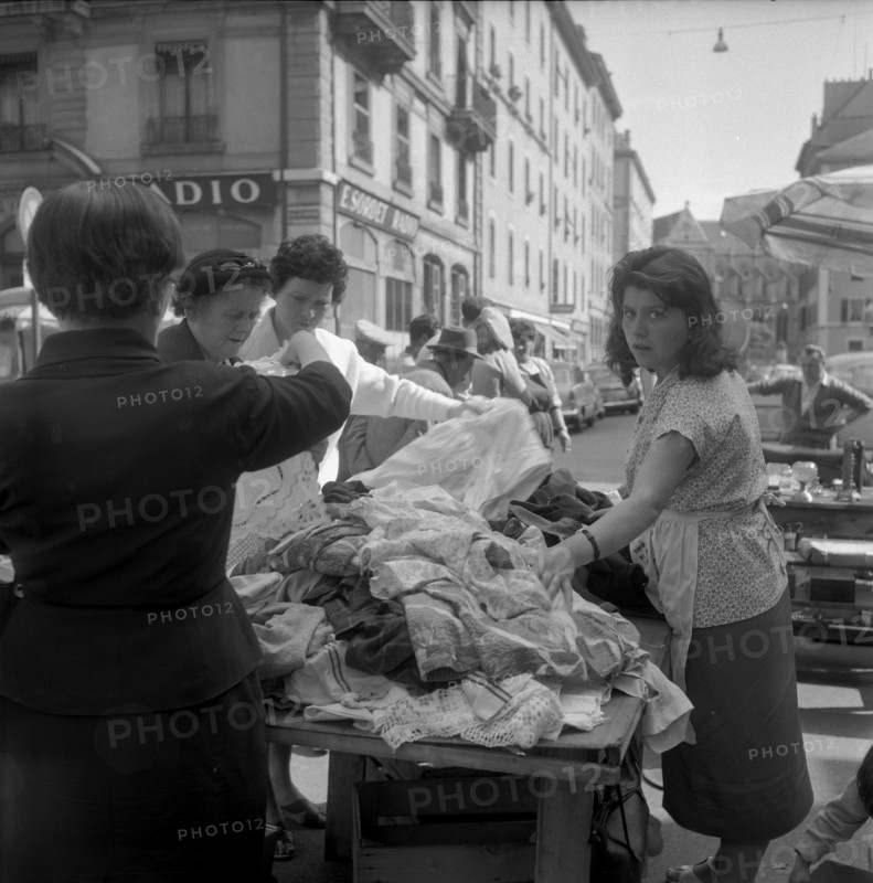 Flea market in Geneva, women examining white goods; 1959