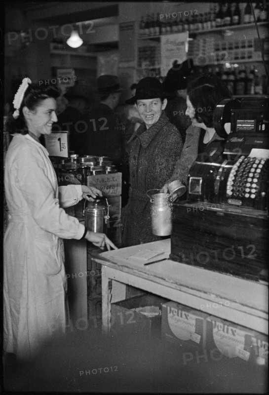 Saleswoman serves customers in a grocery store; 1945