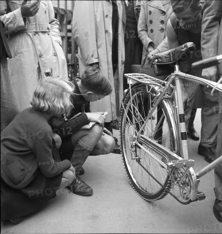 Children examine bicycle tires reinforced with aluminum; 1942