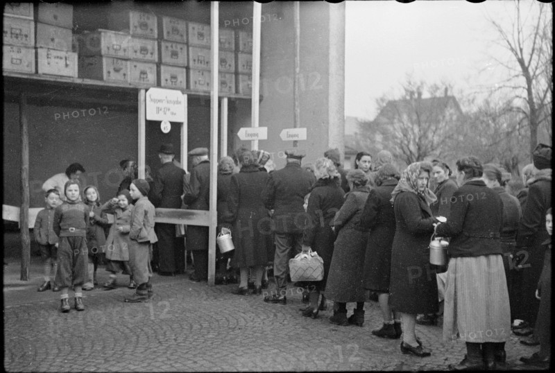 People queue up in front of public kitchen,  giving out soup; 1945.