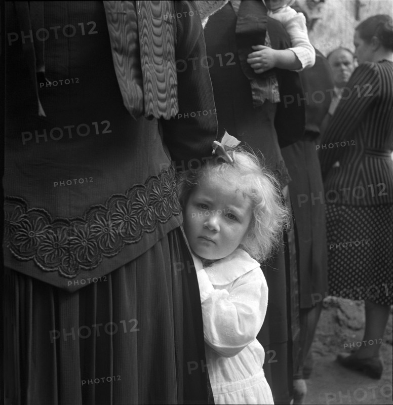 Little girl hanging on to her mother, 1942.