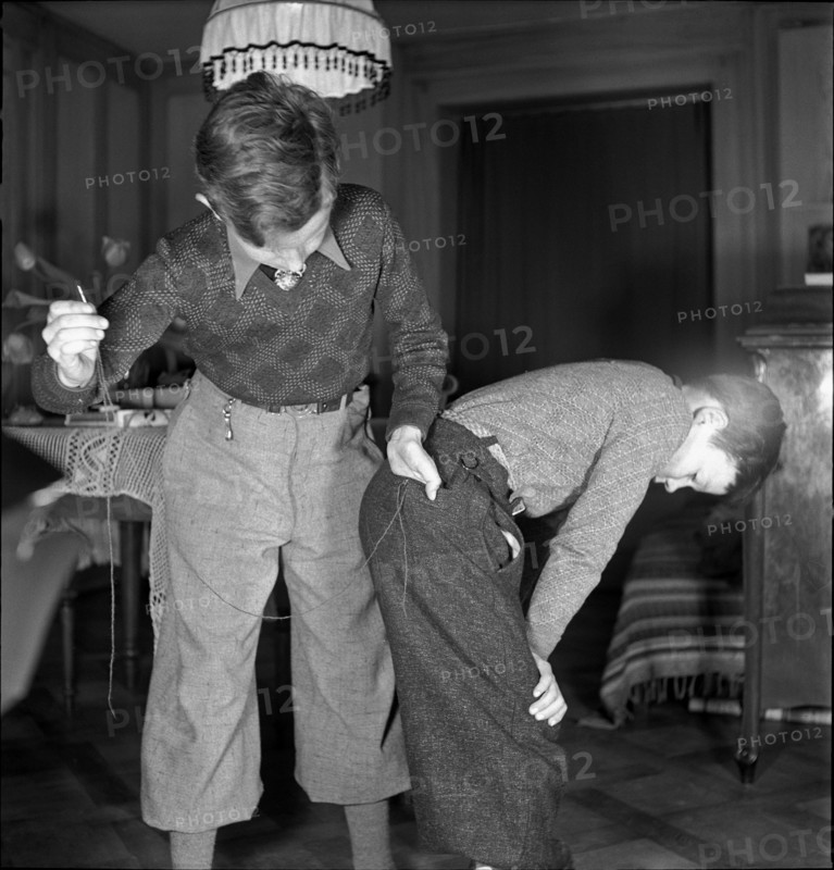 Boy mending his brother's trousers on Mother's Day, 1941.