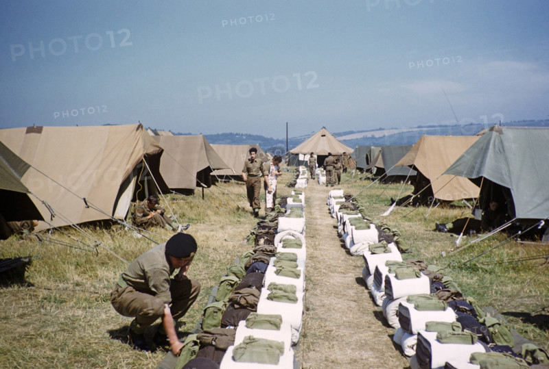 Schoolboys engaged in military training exercises as army cadets, southern England, UK, late 1950s boys lining up kit for inspection in front of their tents at campsite.