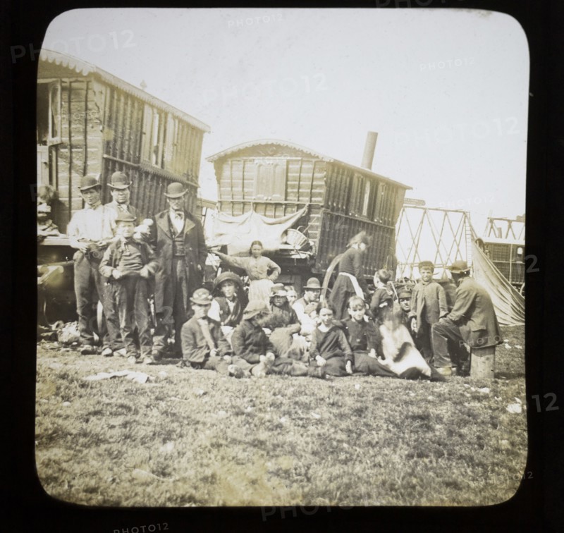 Magic lantern slide portrait of fairground travelling gypsy extended family and caravans, UK circa 1900.