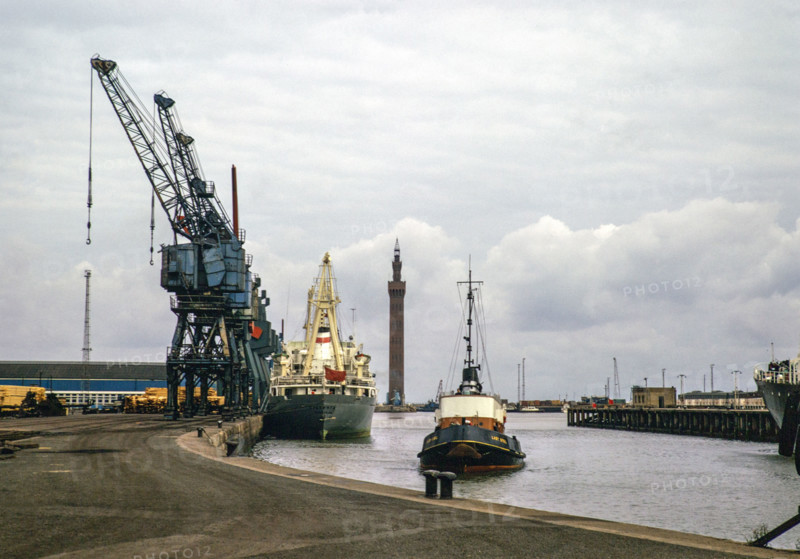 Cargo ships and 'Lady Sybil' tug boat, Royal Dock with Grimsby Dock Tower, Grimsby, Lincolnshire, England, UK September 1973.