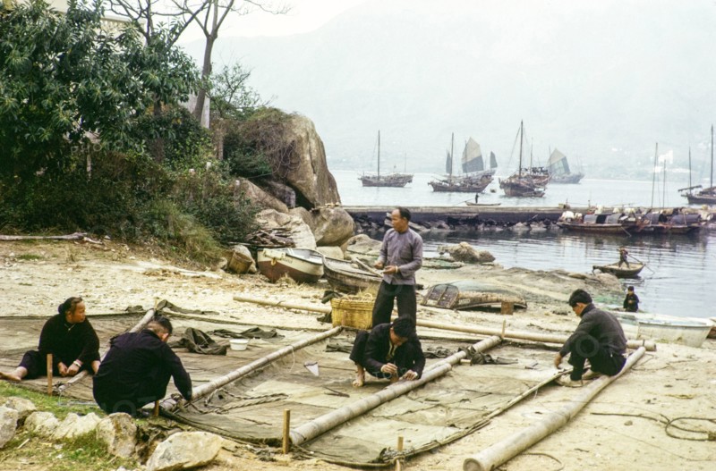 People on beach repairing their junk boat sail, Castle Peak, New Territories, Hong Kong, Asia, 1964.