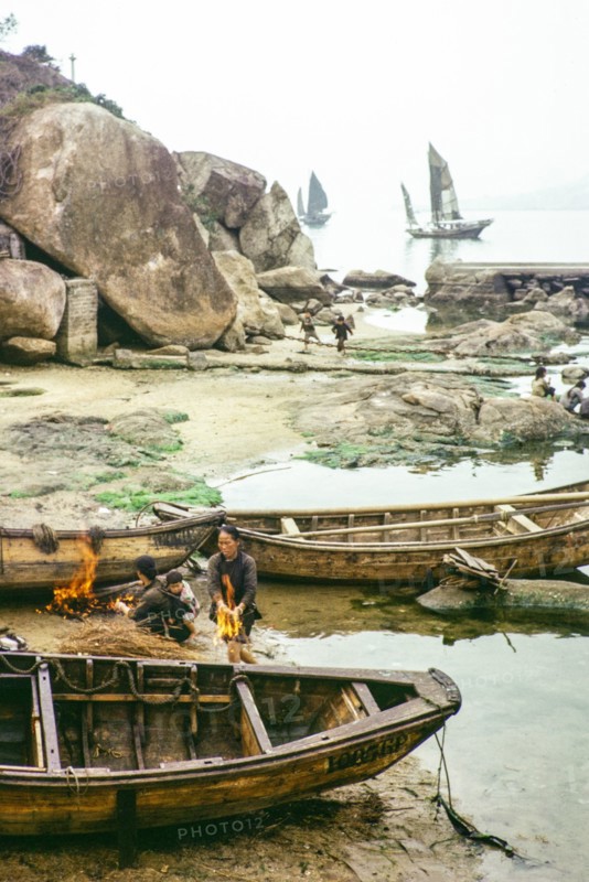 Cleaning the hull of a boat with flames from a small fire in a process known as breaming, Castle Peak, New Territories, Hong Kong, Asia, 1964.