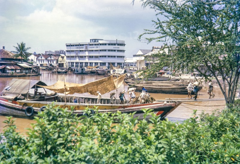 Unloading sacks from cargo boat on Singapore River, Singapore, southeast Asia c 1963 Sime Darby Ltd Godown warehouse  in background.