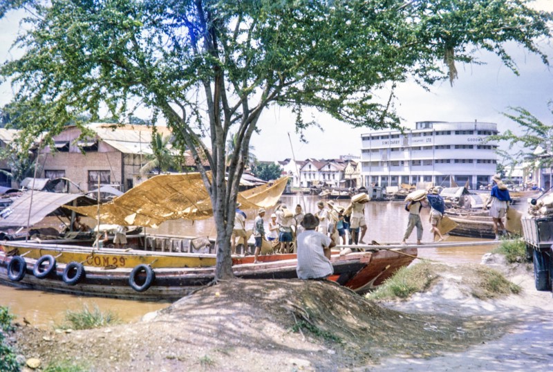 Unloading sacks from cargo boat on Singapore River, Singapore, southeast Asia c 1963 Sime Darby Ltd Godown warehouse in background.