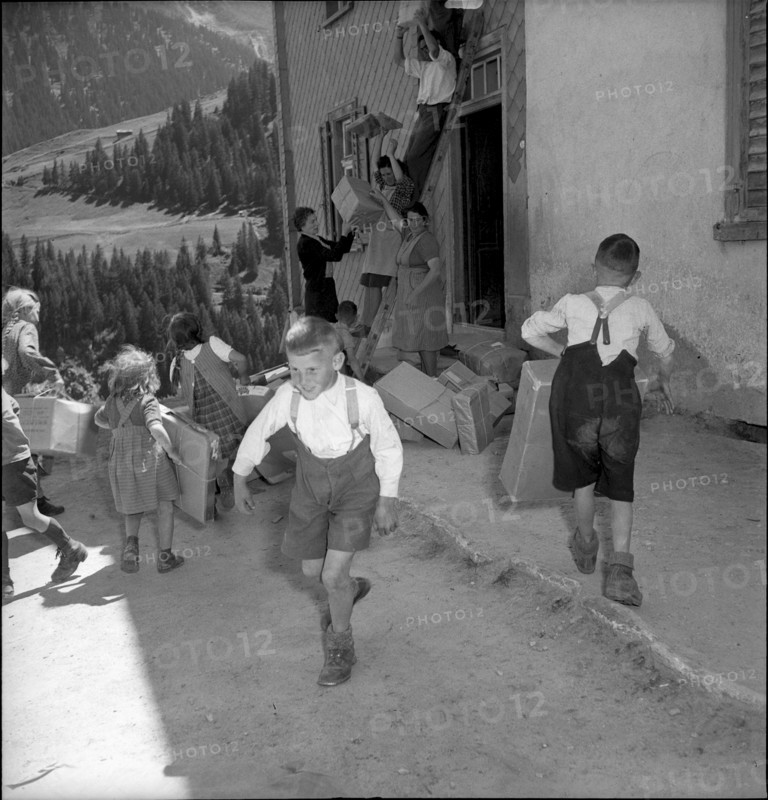 Children carrying parcels, relief supplies for the population of the completely burned down hamlet Selva 1949