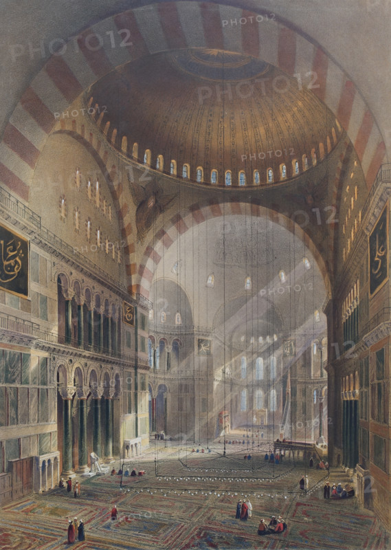 General view of the large nave, facing east of Ayasofya Mosque with groups of men in traditional dress.