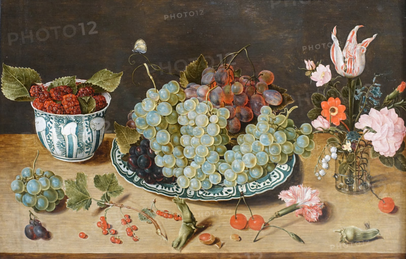 Still life with grapes, berries and a bouquet of flowers.