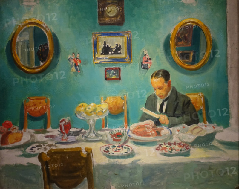 The artist Mstislav Valerianovich Dobuzhinsky at the table.