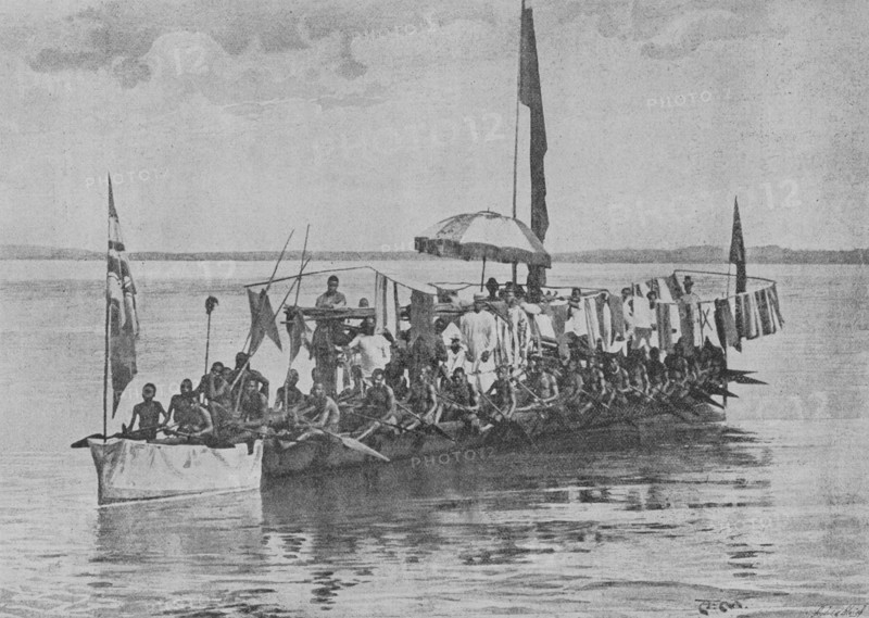 Frederick William Koko Mingi VIII of Nembe (1853-1898), known as King Koko and King William Koko. African ruler of the Nembe Kingdom (also known as Nembe-Brass) in the Niger Delta, now part of southern Nigeria. King Koko Mingi VIII war canoe on the Brass River. Captured enemy flags used to adorn the deck. Photogravure by Andre & Sleigh. ""La conquista de Africa"" (The conquest of Africa), by Alfredo Opisso. Volume II. Published in Barcelona (Spain) by Molinas y Maza editores, 1911.