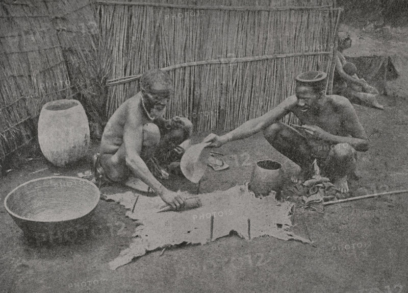 South Africa. Zulu preparing a skin for wear. Photogravure from a photograph by Mr. G.T. Ferneyhough, F.R.G.S. Pietermaritzburg. ""La conquista de Africa"" (The conquest of Africa), by Alfredo Opisso. Volume III. Published in Barcelona (Spain) by Molinas y Maza editores, 1911.