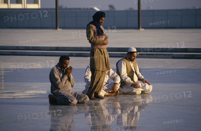 PAKISTAN, Islamabad, "Faisal Mosque. Four men at prayer, reflected in surface of  shiny marble floor."