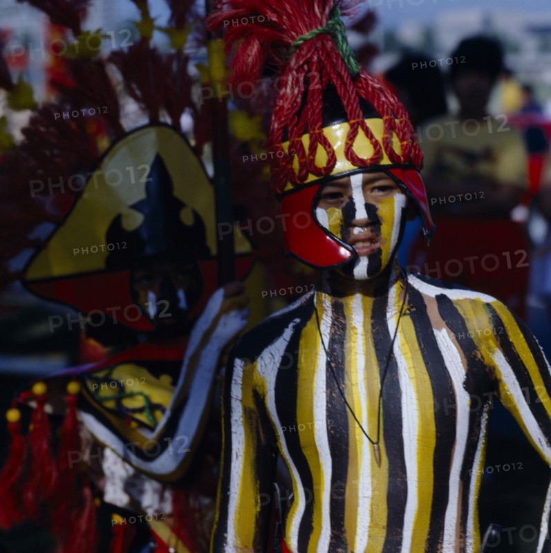 PHILIPPINES, Luzon, Manila, Boy at Ati-Atihan  festival with striped painted body and wearing a red headdress