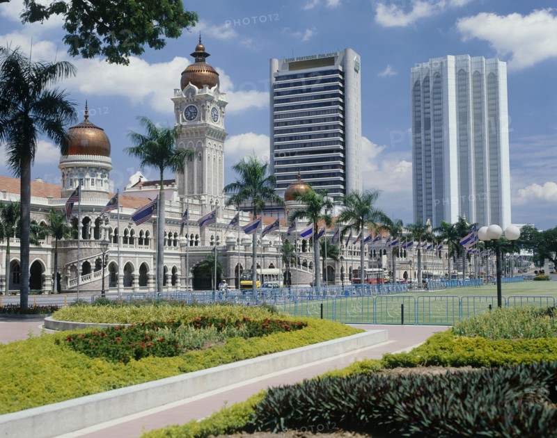 MALAYSIA, Peninsular, Kuala Lumpur, Sultan Abdul Samad building with its copper domes and skyscrapers beyond  with flower beds in the foreground