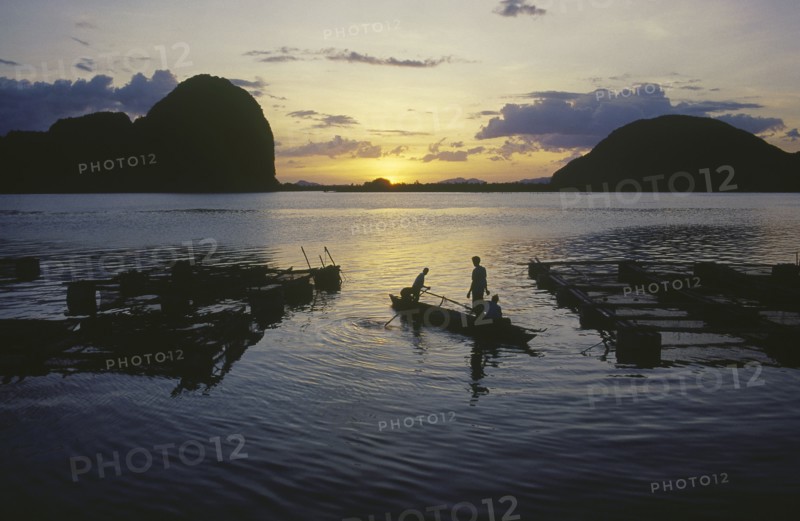 THAILAND, Phang Nga, Fish farm at sunset with two men in a canoe