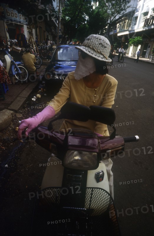 VIETNAM, Ho Chi Minh City, Woman on moped wearing a scarf over her nose and mouth to protect against the smog