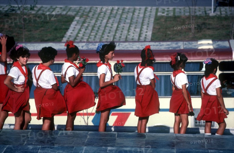 CUBA, Santa Clara, School children wearing red and white uniforms standing in line with some holding red roses
