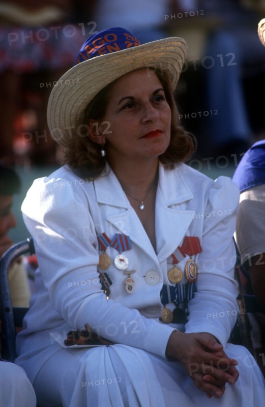 CUBA, Santiago, Seated woman dressed in white with medals pinned to the front of her jacket