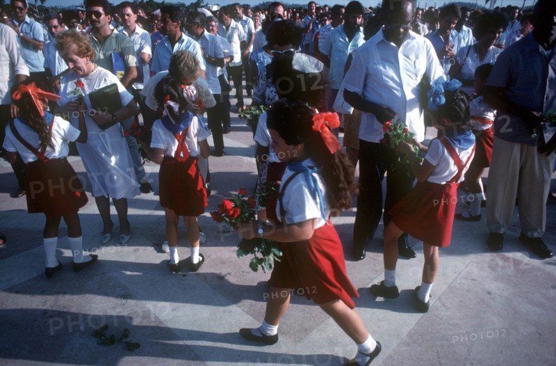 CUBA, Santa Clara, School children wearing red and white uniforms distributing red roses to adults
