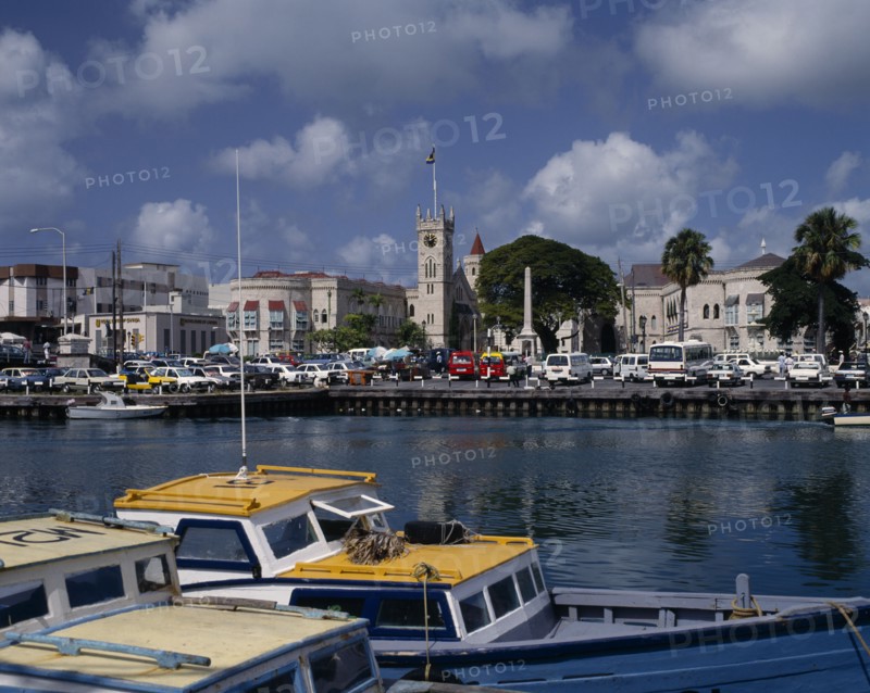 BARBADOS, Bridgetown, "The Carenage seen from across the sea  with buildings,church tower,cars, boats on water in foreground"