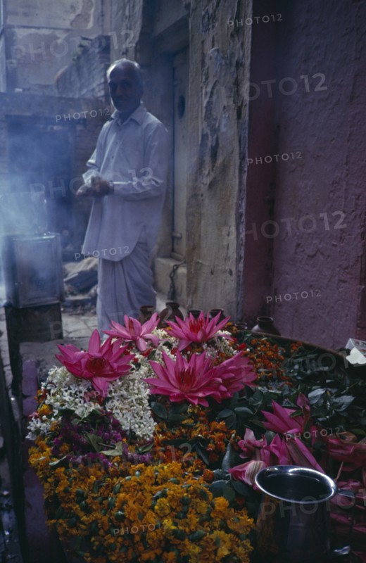 INDIA, Uttar Pradesh, Varanasi, Man standing by display of flowers and burning incense