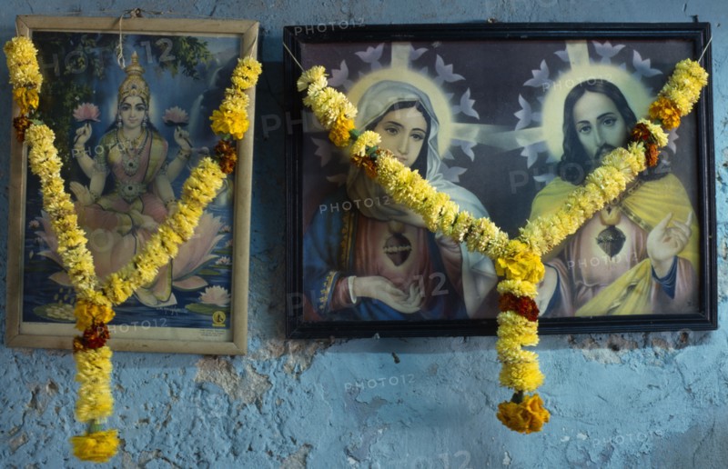 INDIA, Religion, Christian / Hindu, Framed pictures of Hindu and Christian iconography hung with marigold flower garlands.