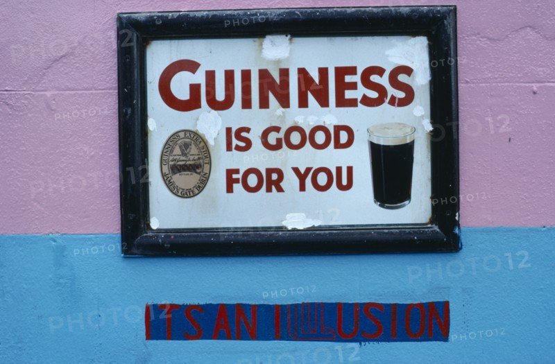 IRELAND, General, "Dan Foleys pub sign saying Guinness is Good for You, with the words Its an Illusion painted on the wall underneath"