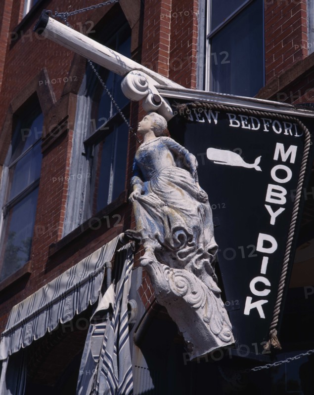 USA, Massachusetts, New Bedford, Moby Dick'hanging sign with ships figurehead on a brick building