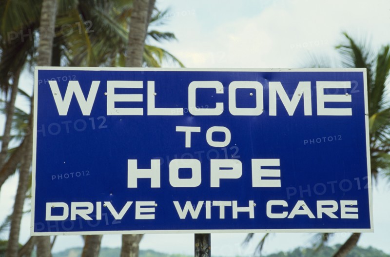 WEST INDIES, Tobago, Hope, Blue and white roadsign outside village reading Welcome To Hope Drive With Care