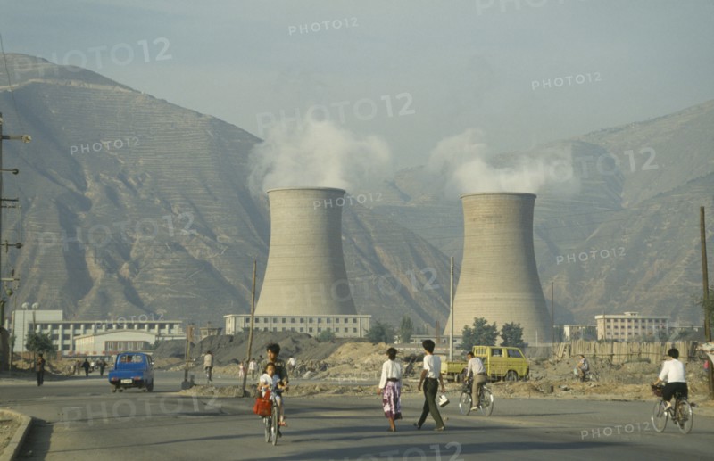CHINA, Gansu Province, Lanzhou, Coal Power Station with people walking in the foreground.