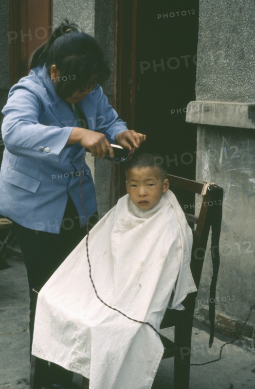 CHINA, Guanzhou, Barber cutting young boys hair