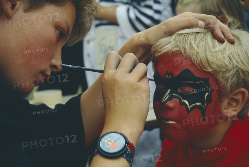 CHILDREN, Play, Face Painting, Young boy having his face painted with bat design.