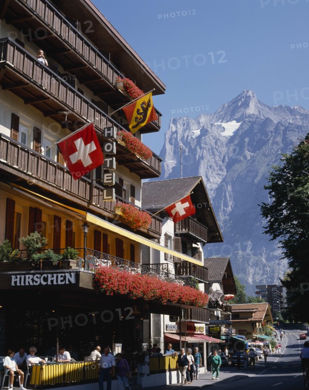 SWITZERLAND, Bern Oberland, Grindelwald, Main street and hotel e distancewith flags on the balconies and a snowcapped mountain