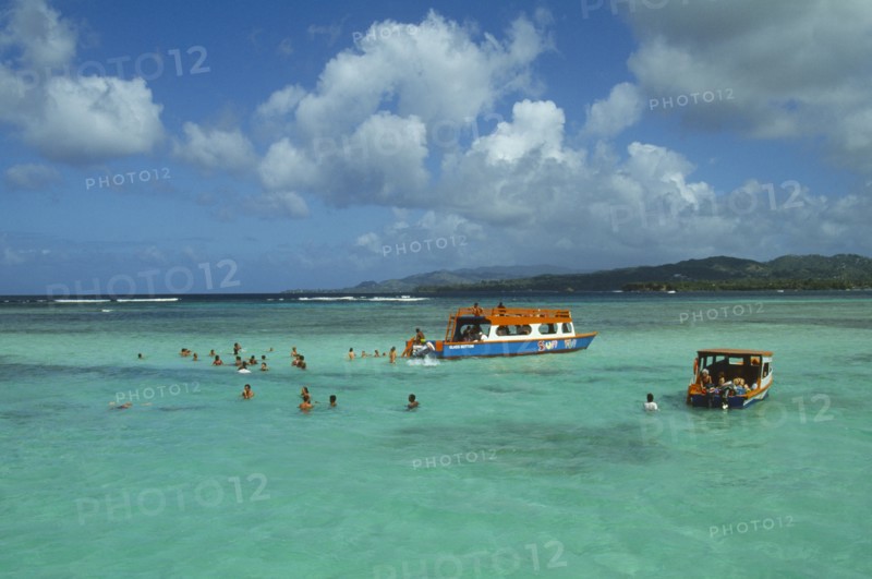 WEST INDIES, Tobago, Buccoo Reef, Nylon Pool with tourists swimming or standing in shallow water by boats