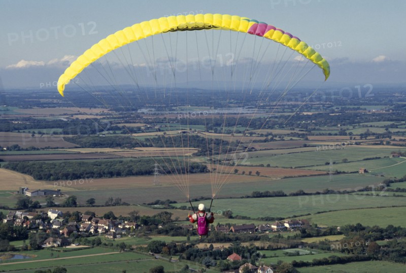 10037037 SPORT Air Paragliding Paraglider with yellow chute and landscape below.