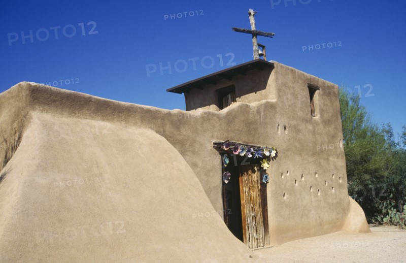 USA, Arizona, Tucson, De Grazias Mission church exterior with plain sandstone walls and floral decoration around the doorway.