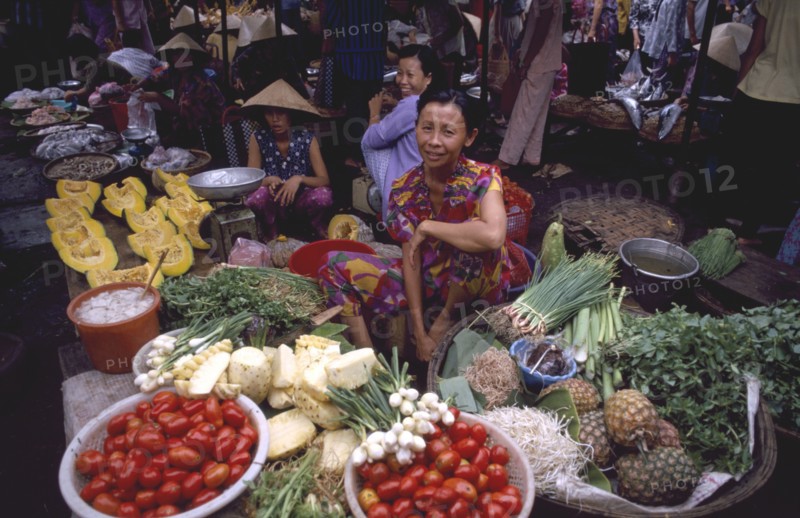 VIETNAM, South Central, Khanh Hoa Province, Nha Trang. Vegetable market vendor sitting behind displays of goods