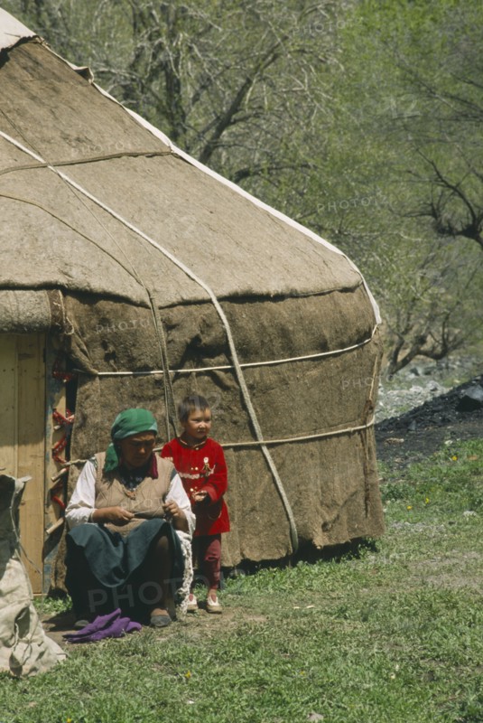 CHINA, Xinjiang, Tianchi, "Kazakh Yurt , tent, with woman and young boy outside a wooden door"