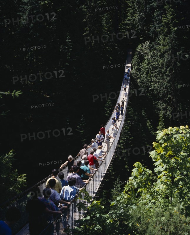 CANADA, British Columbia, Vancouver, Capilano Suspension Bridge with tourists crossing the tree lined gorge