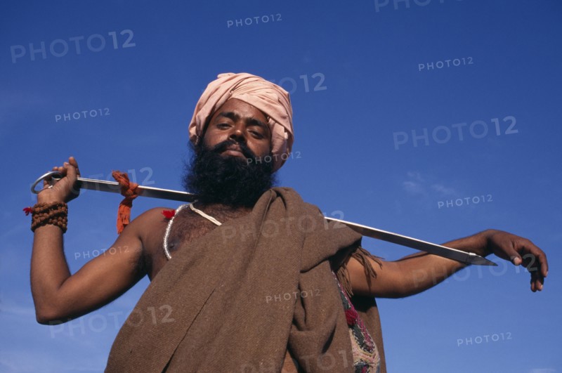 INDIA, Delhi , SIkh man holding Holy Kirpan Sword for the defence of the weak.  Three-quarter view looking up from below.
