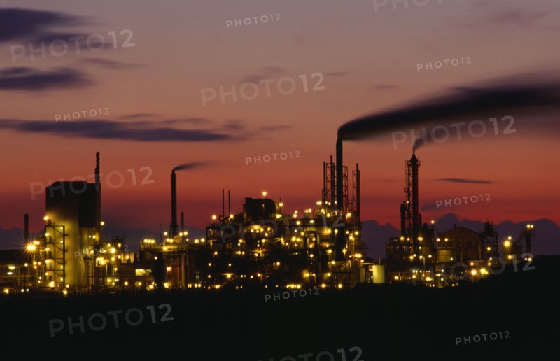 INDUSTRY, Factory, Refinery, Grimsby petrochemical plant illuminated at dusk.  Buildings and smoke from chimneys silhouetted against  pink and orange sky.
