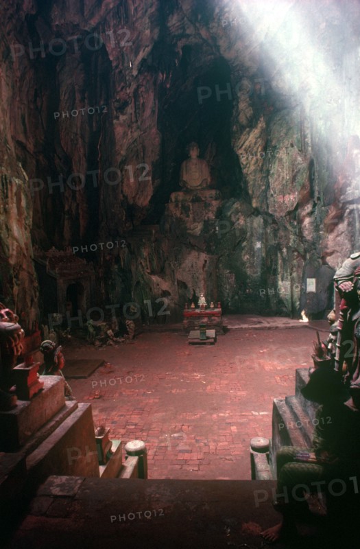 VIETNAM, Danang, Cave Temple in the Marble Mountains.  Looking towards altar and seated Buddha above set into rockface.
