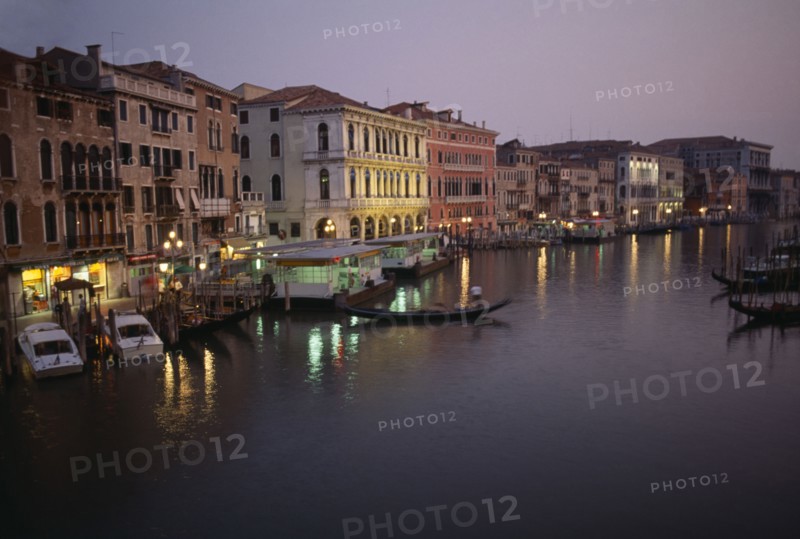 ITALY, Veneto, Venice, The Grand Canal at night with lights reflected in the water. Moored gondolas and boats.