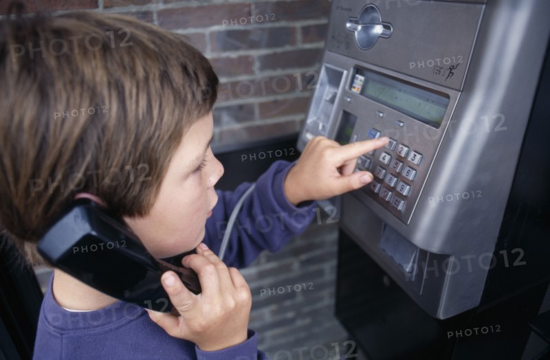 COMMUNICATIONS, Phones, Payphone, Young boy dialing on a payphone