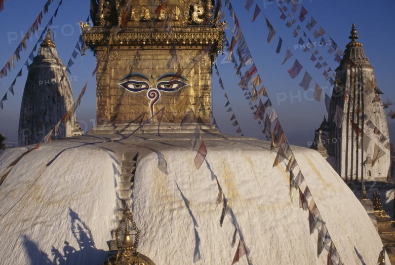 NEPAL, Kathamndu Valley, Swayambhunath, Swayambhunath Temple roof with painted eyes of Buddha and hung with prayer flags.